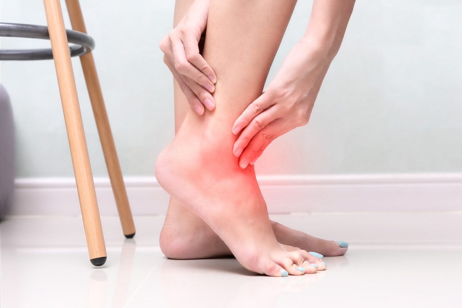 An ankle is held with both hands, indicating pain with a red glow.