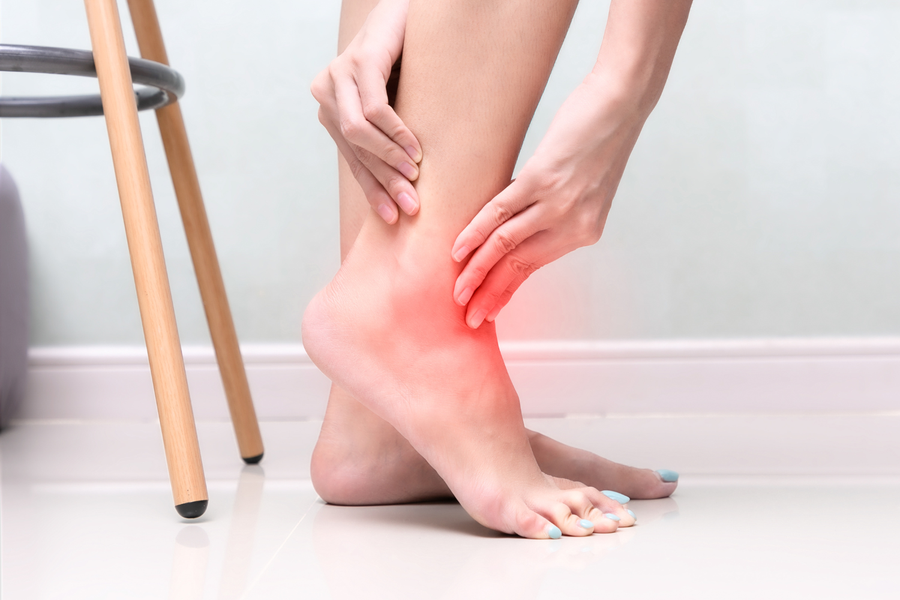 An ankle is held with both hands, indicating pain with a red glow.
