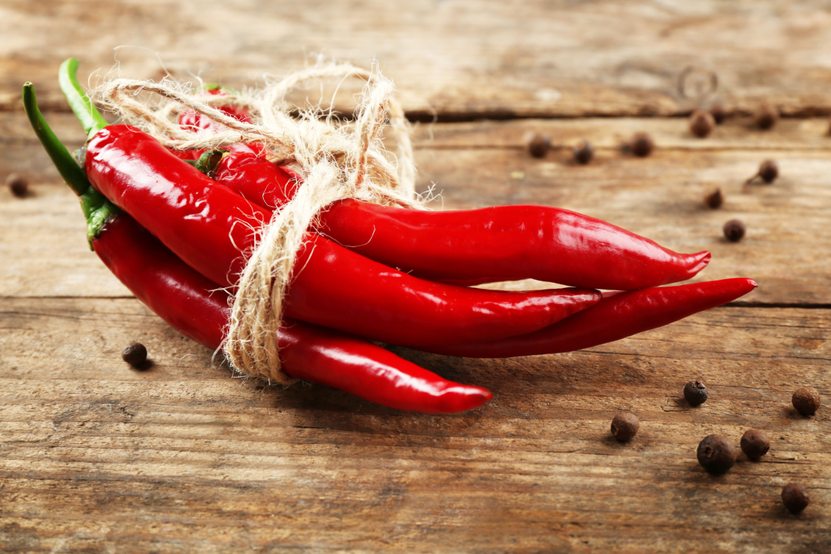 Image of fresh cayenne peppers on a wooden table.