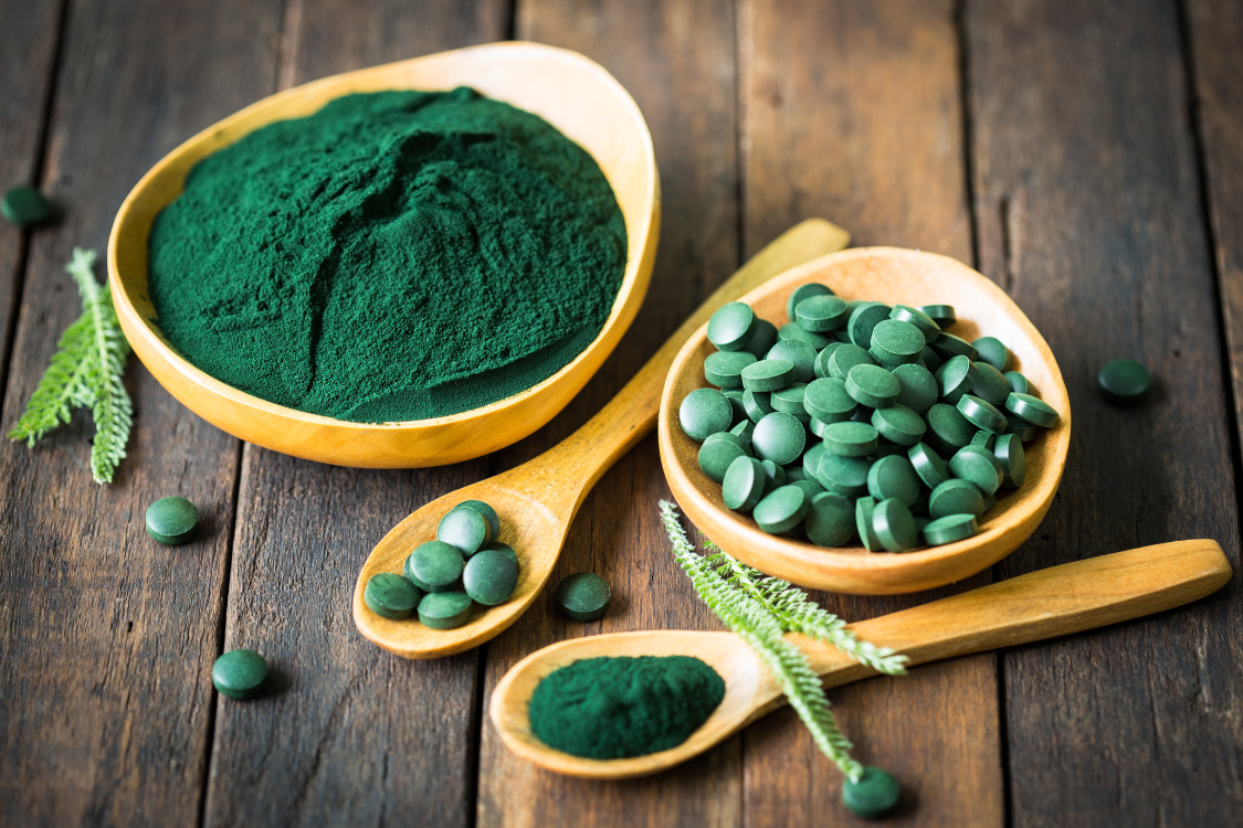 chlorella powder in wooden scoop on stone background