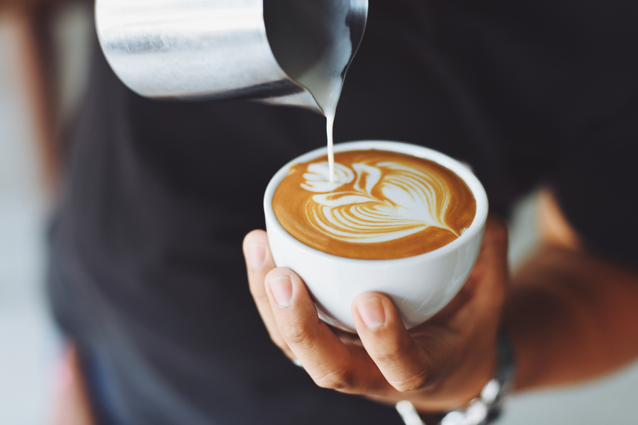 A barista pours milk into coffee, showing how daily coffee habits can fit into a kidney-conscious routine.