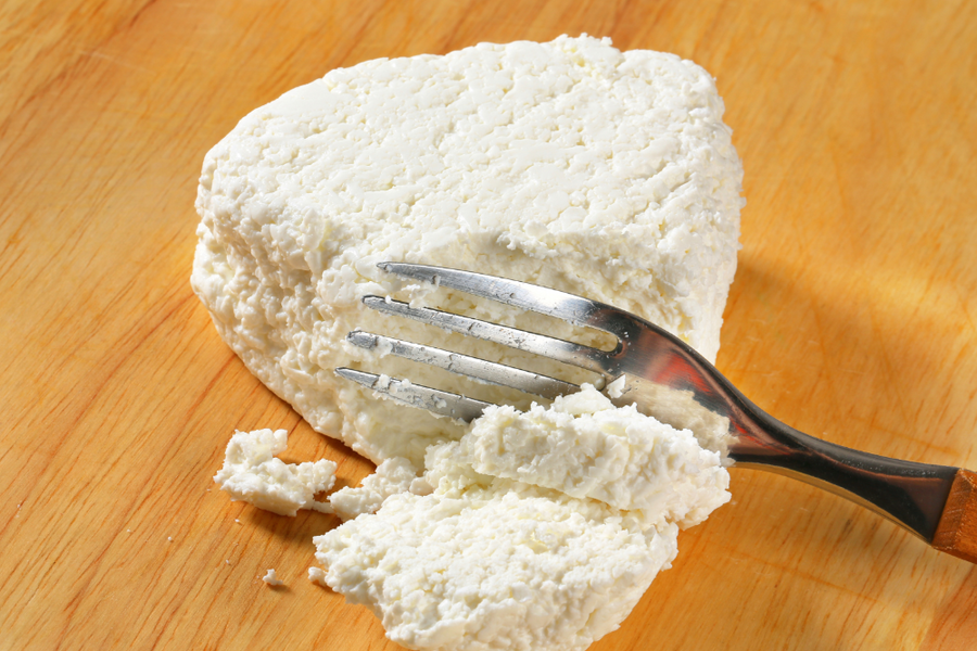 A fork is breaking apart a block of cottage cheese for gout.