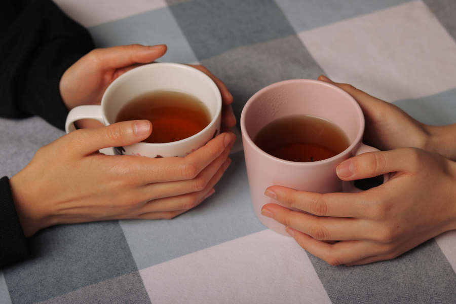 Two people holding mugs of herbal tea, promoting kidney health through hydration