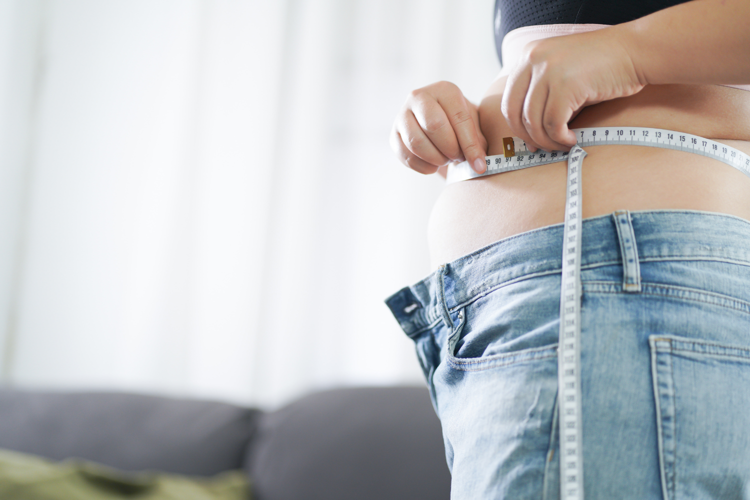 Woman measuring her waist with a tape measure.