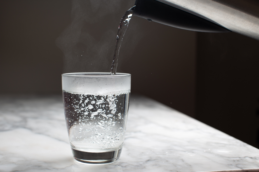 Hot water being poured into a glass, highlighting hydration habits for gout management