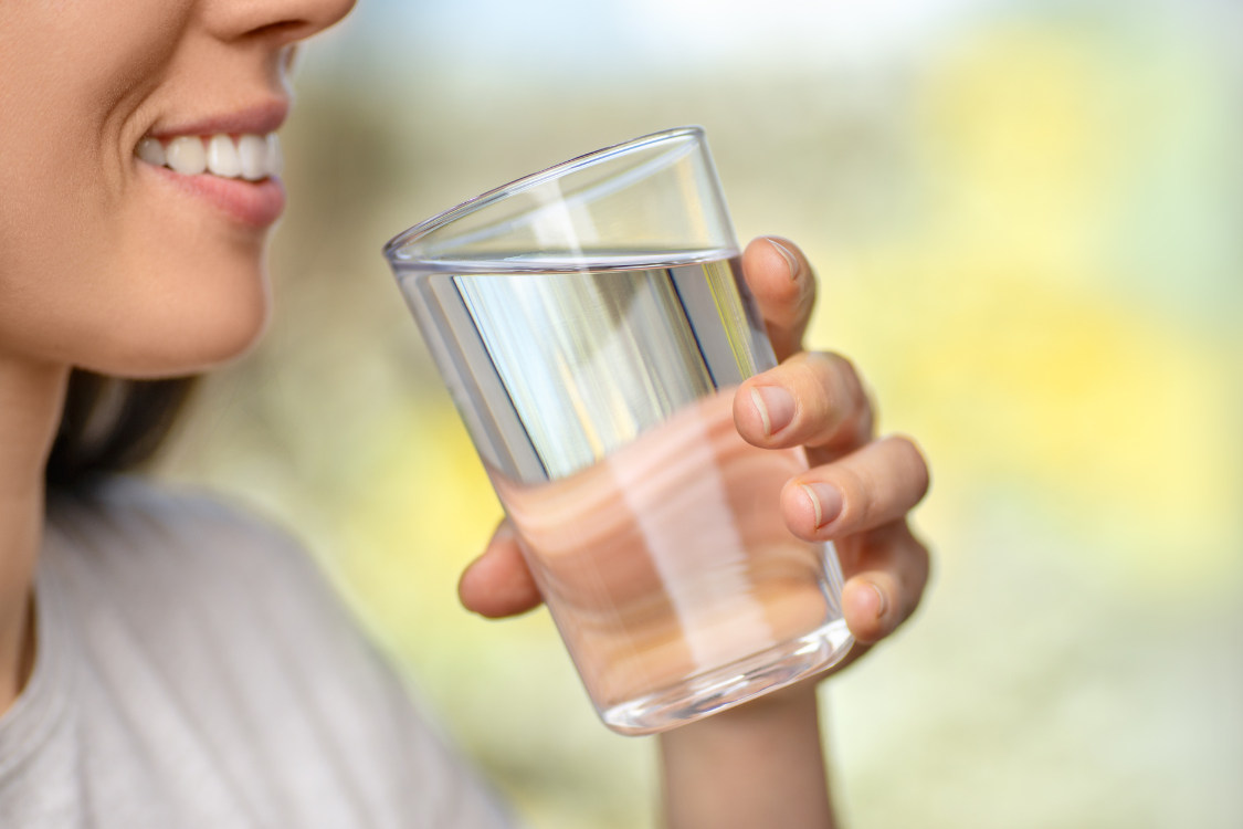 A person holding a glass of water for hydration and kidney wellness.