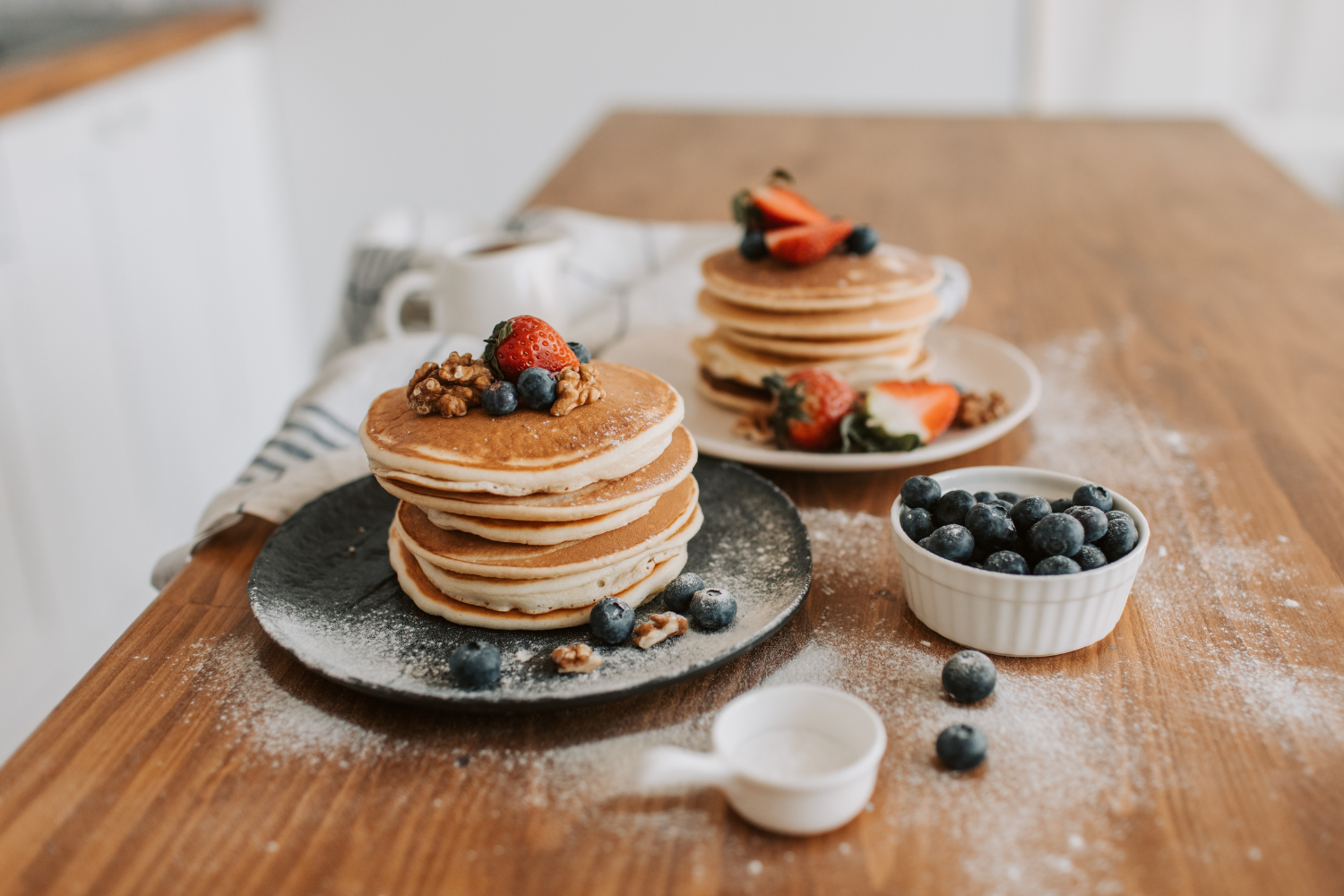 Stack of delicious pancakes with berries and powdered sugar.