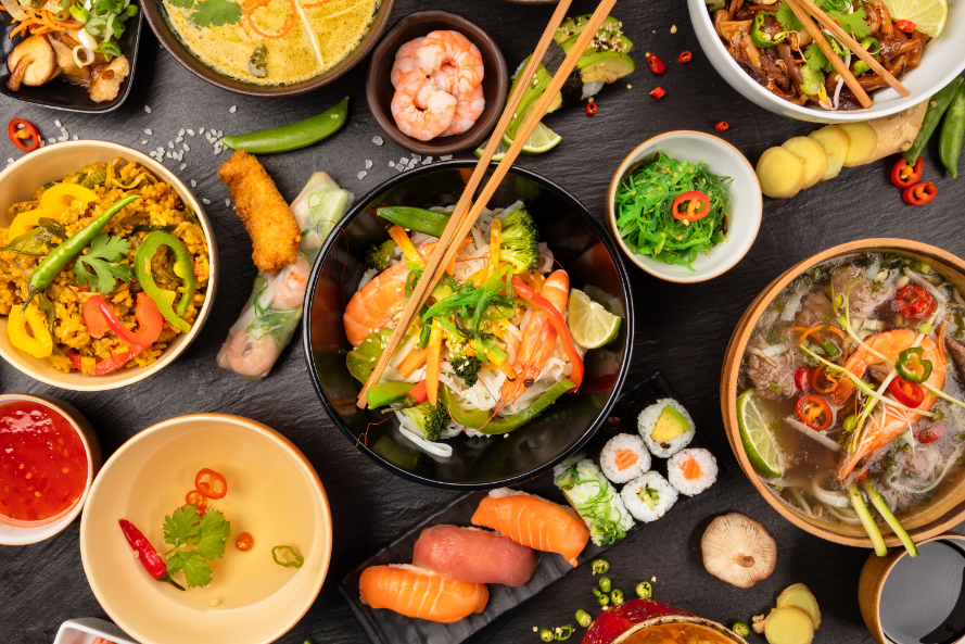 Assortment of Asian-inspired dishes including sushi, noodle soups, and seafood, highlighting purine-rich foods such as tuna, salmon, shrimp, and meat-based meals.