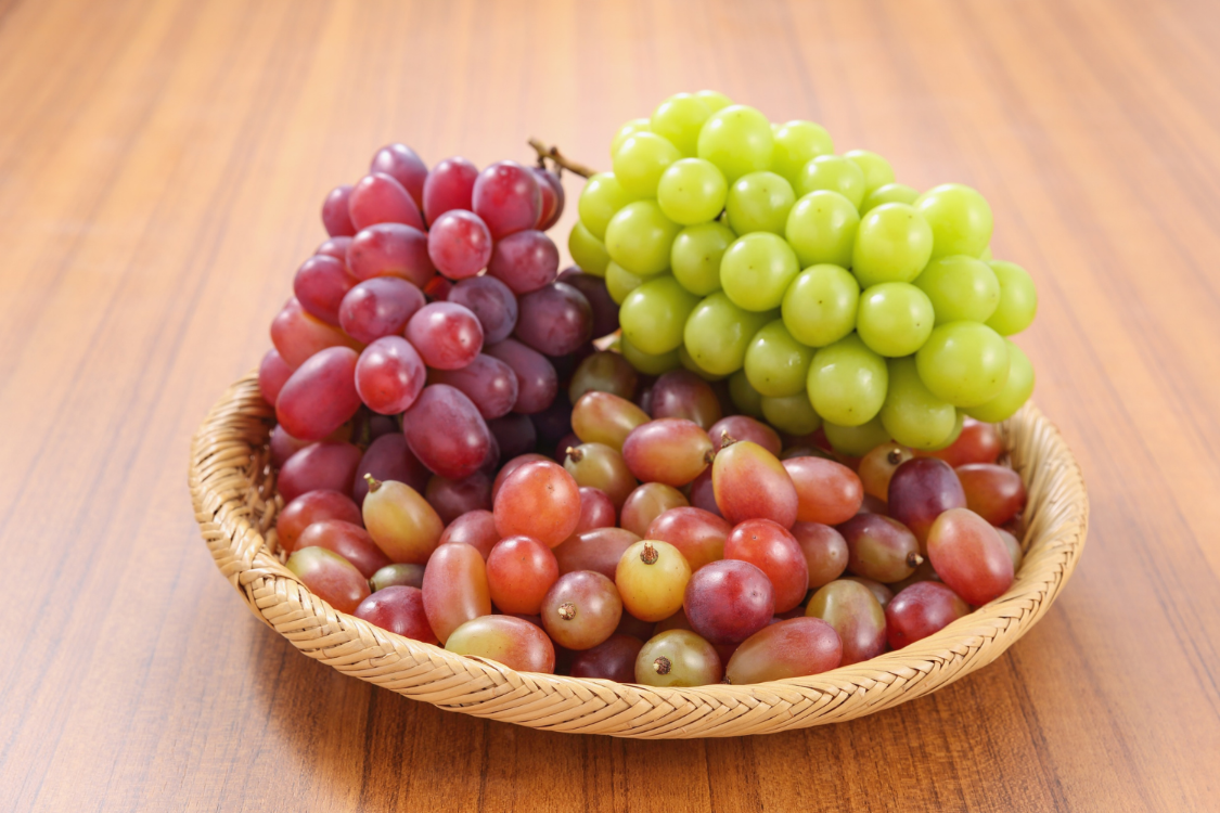 A basket holding red and green grapes, representing a fruit that should be eaten in small portions as part of a gout-friendly diet.