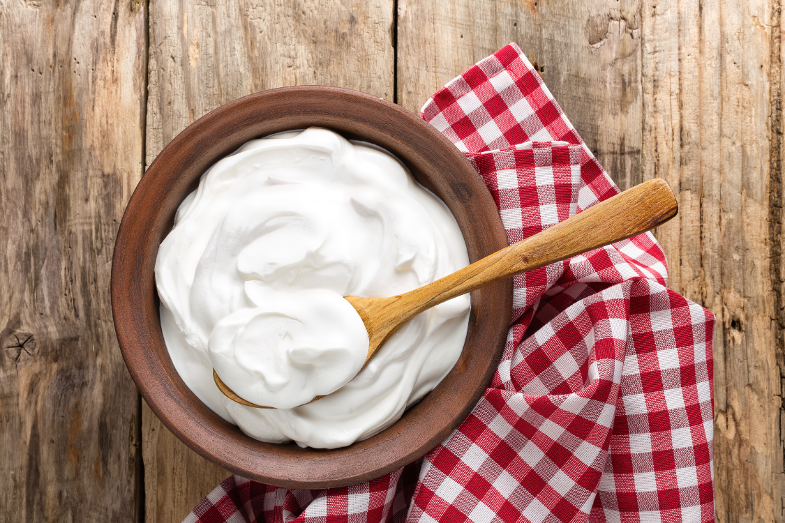 Overhead view of a ceramic bowl filled with thick, plain Greek yogurt, a high-protein option for gout relief.