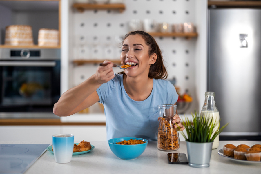 Woman enjoying a bowl of whole grain cereal, a gout-friendly snack option that supports kidney health
